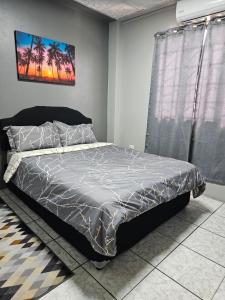 um quarto com uma cama com um edredão cinzento em In-flight Suites - Perfect for Layovers 6Mins from the Airport em Piarco