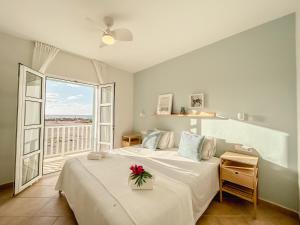 Papaya Apartments Boa Vista في سال ري: غرفة نوم عليها سرير مع وردة