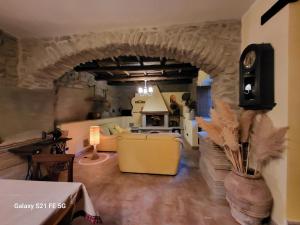 a living room with a stone archway and a yellow couch at Casale I Pioppi in Vitorchiano