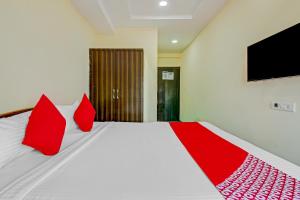 um quarto com uma cama com almofadas vermelhas e uma televisão em OYO Adhin Residency em Hyderabad
