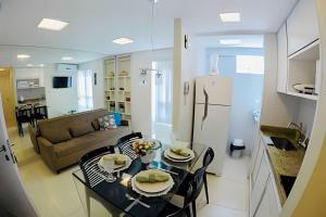 cocina y sala de estar con mesa y nevera en Apt à Beira-Mar Cabo Branco c ótima área de lazer, en João Pessoa