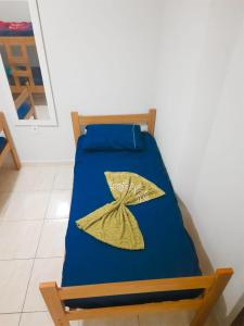 a bed with a blue sheets and a yellow pillow at Casa Maria Vitória in Aparecida