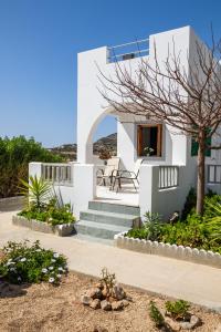 een wit huis met een trap en een boom bij Perama Hotel, Karpathos in Amoopi