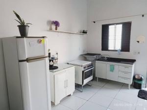 a white kitchen with a refrigerator and a sink at Apartamento Loft 03 Ponta Porã MS. in Ponta Porã