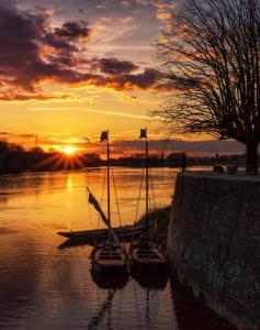 tres barcos sentados en el agua al atardecer en Appartement rez de chaussée avec parking privé, en Orléans