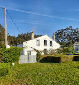 ein weißes Haus mit einem Zaun im Hof in der Unterkunft casa de campo adosada 2 in Viveiro