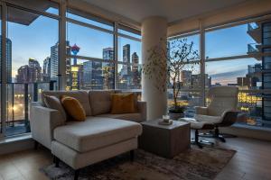 uma sala de estar com um sofá e uma grande janela em Luxury Corner Unit w Panoramic Tower & Downtown Skyline Views! FREE Banff Pass, Wine, Gym & Parking! em Calgary