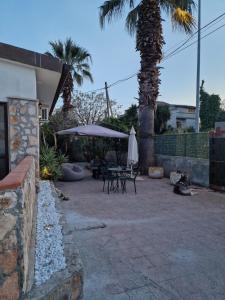 a patio with a table and umbrella and a palm tree at Villa "OLD FISHERMAN'S" in Taranto