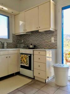 a kitchen with white cabinets and a stove top oven at Villa Sis in Aïdhónia