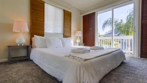um quarto com uma grande cama branca e uma grande janela em B5021 South Mission Beach House em San Diego