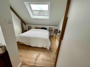 - une chambre avec un lit blanc et une lucarne dans l'établissement Maison familiale au calme, à Lorient