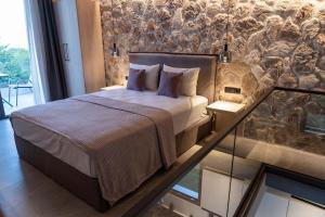 ein Schlafzimmer mit einem Bett und einer Steinmauer in der Unterkunft SUNRISE VILLAS PLATAMON in Platamonas
