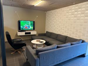 uma sala de estar com um sofá azul e uma televisão em Det gamle snedkeri em Ribe