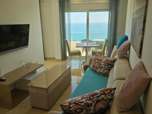 ein Wohnzimmer mit einem Sofa, einem TV und einem Tisch in der Unterkunft Apartments D'Hermes in Ulcinj