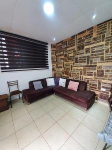 a living room with a couch and a stone wall at SUITE AMOBLADA CERCA DEL MALL DEL RIO in Cuenca