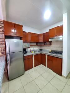 La cuisine est équipée d'armoires en bois et d'un réfrigérateur en acier inoxydable. dans l'établissement SUITE AMOBLADA CERCA DEL MALL DEL RIO, à Cuenca