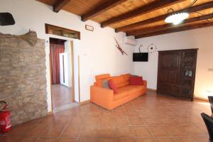 un soggiorno con divano arancione e parete in pietra di Villa Andrea "Vivi l'Oasi di Tranquillità" a Trapani