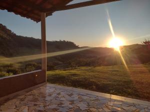 Aussicht von der Veranda eines Hauses mit Blick auf den Sonnenuntergang in der Unterkunft Chalés Recanto das Flores in Bueno Brandão