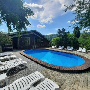 a swimming pool with lounge chairs and a house at Садиба "333" in Yaremche