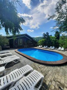 a swimming pool with white lounge chairs around it at Садиба "333" in Yaremche