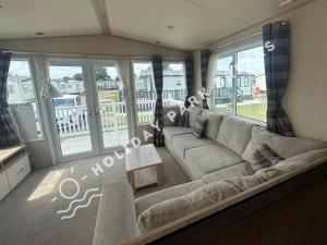 a living room with a large couch and windows at Modern 3 bed; West Sands @ Seal Bay Resort in Chichester