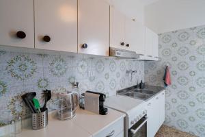 uma cozinha com armários brancos e um lavatório em Comodo Trilocale a Pietra Ligure em Pietra Ligure