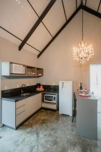 a kitchen with a white refrigerator and a table at Recanto Fogo na Taça (Chalé das Oliveiras) in Jaraguá do Sul