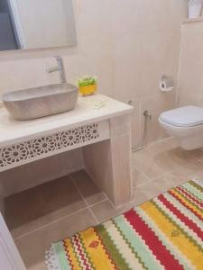 a bathroom with a sink and a toilet and a rug at Dar selim in Midoun