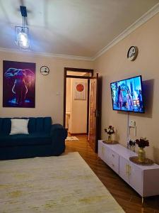 a living room with a blue couch and a flat screen tv at Vogue Homes in Nakuru