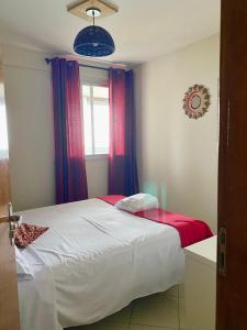 - une chambre avec un lit doté de rideaux rouges et bleus dans l'établissement Beachfront apartment, à Vila Velha