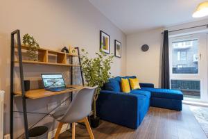 een woonkamer met een blauwe bank en een bureau met een laptop bij Luxury Campbell Park Apartments in Central MK with Balcony, Free Parking & Smart TV with Netflix by Yoko Property in Milton Keynes