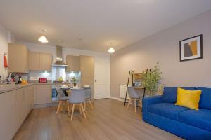 a living room with a blue couch and a kitchen at Luxury Campbell Park Apartments in Central MK with Balcony, Free Parking & Smart TV with Netflix by Yoko Property in Milton Keynes