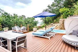 um deque com cadeiras, um guarda-sol e uma piscina em Luxury Beachfront Villa at Punta Flamenco, Culebra, Puerto Rico em Culebra