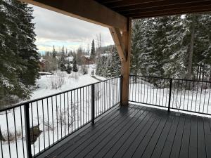 a balcony with a view of a snow covered forest at Whitefish Mountain Marvel Ski in Ski out- New Build, Pool Table, Hot Tub and Sleeps 19! in Whitefish