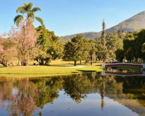 a park with a lake and palm trees and a mountain at Apto 3 quartos, no Centro. Temático e acolhedor! in Nova Friburgo