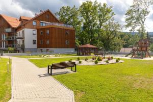 un parque con un banco, un parque infantil y un edificio en Apartament Izerka z basenem i sauną - Stone Hill, en Szklarska Poręba
