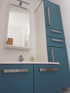 een badkamer met een blauwe kast en een spiegel bij Cosy ecolodge with shared heated pool 10 from the beach in Les Mathes
