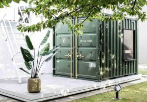 a green shipping container with a potted plant next to it at Whiteloft in Neuwied
