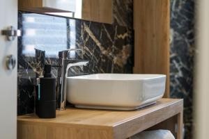 a bathroom sink on a wooden counter with a black tile wall at Holiday House 2 in Viterbo