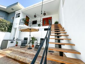 a white house with stairs and an umbrella at Beachfront w/ pool & rancho - Casa Coral in Puntarenas