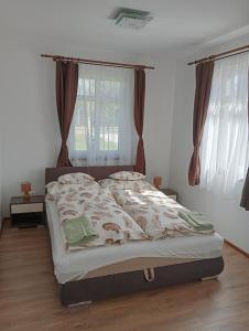 Cama en habitación blanca con ventana grande en Vidéki-Báj Vendégház, en Szentgyörgyvölgy