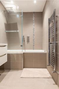 a bathroom with a shower with a tub and a sink at Private room with en-suite in London