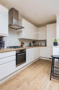a kitchen with white cabinets and a stove at Private room with en-suite in London