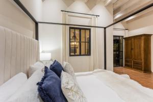 a bedroom with a white bed with blue pillows at Casa Cielo, 4-Story Luxury Home with Rooftop Hot Tub & AC in San Miguel de Allende +32 photos