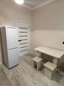 a kitchen with a refrigerator and a table and stool at Уютная квартира рядом с вокзалом Нурлы-Жол in Promyshlennyy