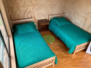 a room with two beds and a night stand and a table at ARRIENDO DIARIO PUQUELDON-CHILOE, SECTOR PLAYA LINCAY in Puqueldón