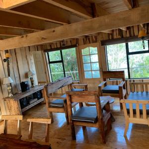 una habitación con sillas y mesas de madera en una cabaña en ARRIENDO DIARIO PUQUELDON-CHILOE, SECTOR PLAYA LINCAY, en Puqueldón