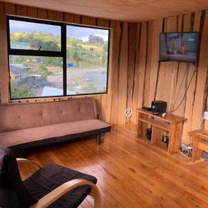 a living room with a couch and a large window at ARRIENDO DIARIO PUQUELDON-CHILOE, SECTOR PLAYA LINCAY in Puqueldón