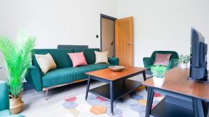 een woonkamer met een groene bank en een tafel bij Primrose House - 3 Bedroom Home in Manchester in Manchester