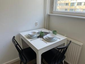 Una mesa blanca con dos tazas y platos. en Garden city studio, en Espoo